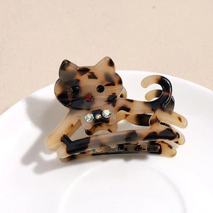 Détail d'une mini pince à cheveux en acétate forme chat avec motif écaille et strass