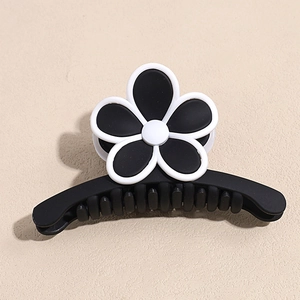 Vue de dessus d'une pince à cheveux noire mate ornée d'une fleur 3D noire et blanche