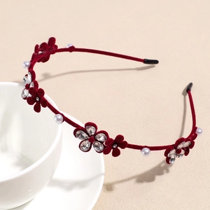Détail du serre-tête en velours rouge avec pétales 3D, perles blanches et strass étincelants