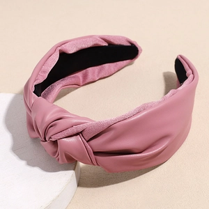 Detail of dusty pink faux leather headband with a stylish knotted design and soft suede edge
