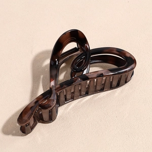 Makroaufnahme der Haarklammer mit Leoparden-Herz-Design und schwarzer Metallfeder