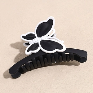 Détail d'une pince à cheveux papillon noire mate avec des accents blancs contrastés
