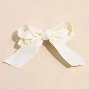 Detail of creamy white grosgrain ribbon texture and classic bow hair clip design