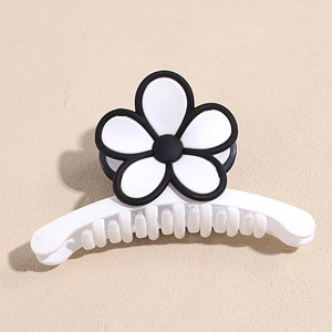 Détail d'une pince à cheveux blanche avec fleur à bord noir et finition en résine mate