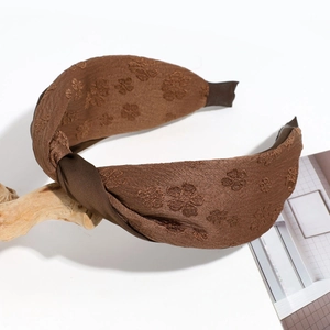 Détail d'un serre-tête vintage noué en tissu avec broderies florales marron