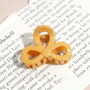 Detail of yellow flower hair claw clip with gold foil texture on vintage magazine background
