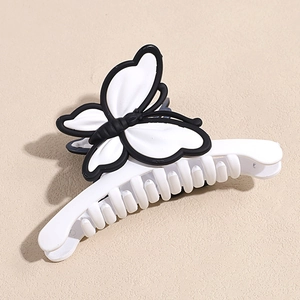 Détail d'une pince à cheveux papillon au design bicolore noir et blanc minimaliste