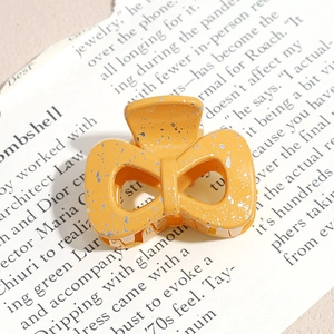 Detailed macro view of yellow butterfly hair claw with silver splatters on magazine
