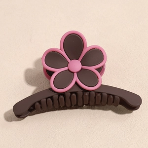 Détail de pince à cheveux fleur café mat avec pétales roses et dents de fixation ferme