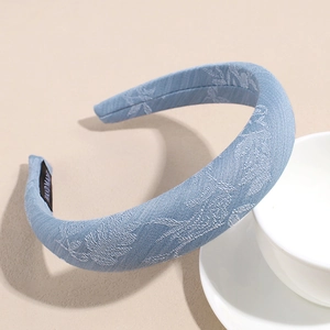 Detail of light blue padded headband with white floral jacquard and handmade inner label
