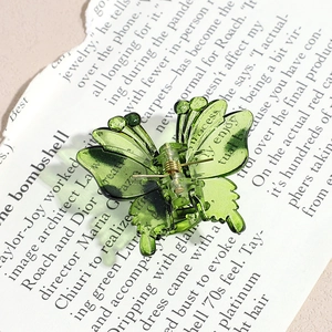 Detailed view of a green gradient butterfly hair claw clip on a vintage magazine base