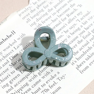 Detailed macro shot of a gray-green hair claw with silver splattered pattern on book pages