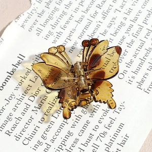 Macro detail of amber butterfly hair claw clip with high-quality resin texture and spring