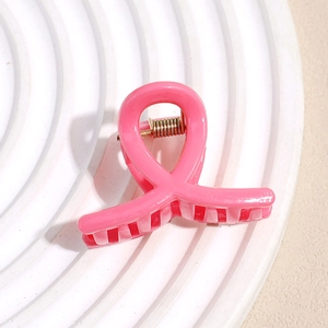 Gros plan sur la pince à cheveux rose en forme de ruban avec finition brillante et ressort