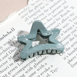 Detailed close-up of a star-shaped sage green hair claw clip with silver glitter accents