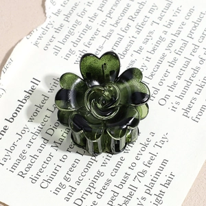 Detailed top view of a dark green translucent rose flower hair claw clip on art paper