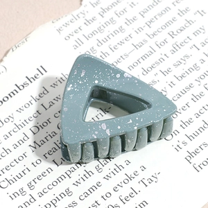 Detail view of a triangle hair claw in grey-blue with silver ink-splash texture