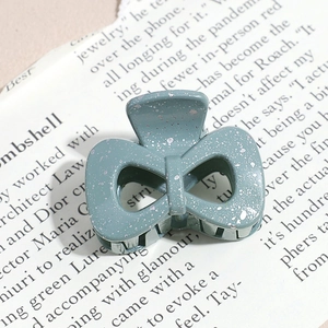 Macro shot of teal bow hair claw with silver sequins on vintage newspaper background