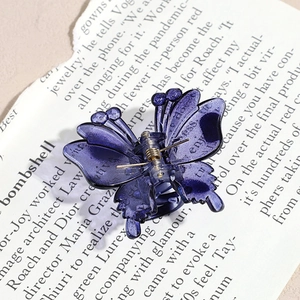 Macro detail of a dark purple butterfly hair claw clip on vintage book pages background