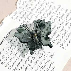 Detail of a dark green marble butterfly hair claw clip with a premium acetate finish