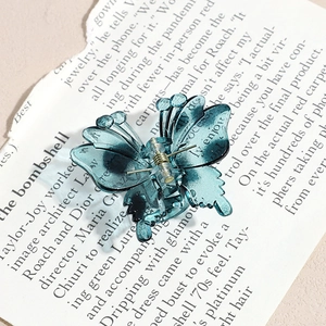 Detailed macro view of the translucent cyan butterfly hair claw clip with golden metal spring
