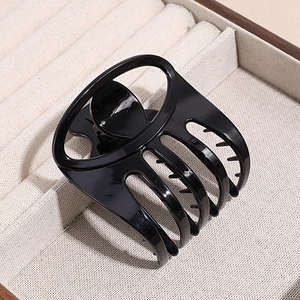 Glossy black hair claw clip with minimalist oval hollow design on ivory tray