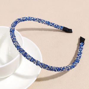 Detail eines schmalen blau-silbernen Glitzer-Haarreifs an einer Keramiktasse ruhend
