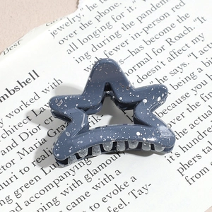 Detail of gray-blue star hair claw clip with silver glitter on vintage newsprint