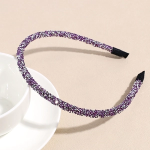 Detail eines schmalen lila und silbernen Glitzerstirnbandes auf weißer Keramiktasse