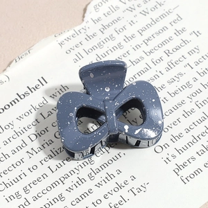 Detail of a dark grey triangle hair claw clip with white splatter pattern on a magazine