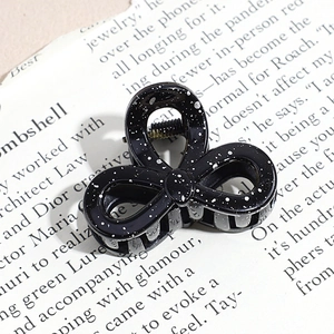Close-up of black triangle hair claw clip with silver ink splatter pattern on retro paper