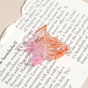 Détail de la pince à cheveux papillon évidée avec dégradé de rose à orange