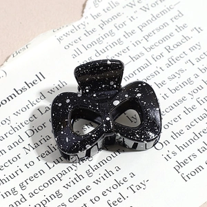 Macro shot of a black and white speckled triangular claw clip on a vintage magazine page
