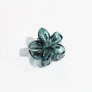 Top view of a translucent dark cyan flower hair claw clip with a glossy finish