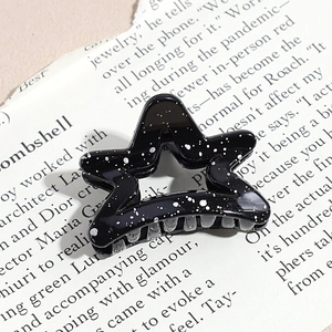 Macro view of star shaped hair claw clip with black galaxy texture and metal spring
