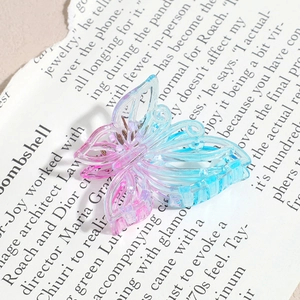 Détail d'une pince à cheveux papillon avec dégradé rose et bleu sur papier design