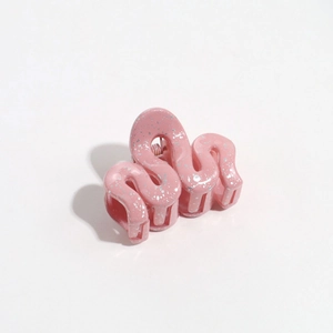 Close-up of pink wave-shaped hair clip with silver glitter and resin finish