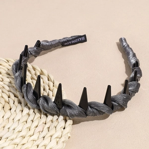 Detailed shot of handmade grey braided headband with black spikes and silver glitter finish