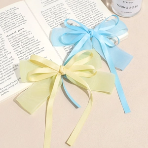 Elegant set of two oversized bow hair clips with long ribbons in soft blue and yellow satin