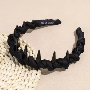 Close-up of handmade black spiked headband with pleated fabric and triangle studs