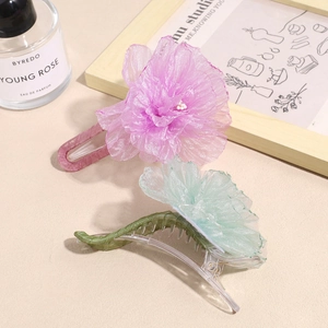 Elegant organza flower hair clips in pink and green displayed with aesthetic props