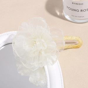 Detailed macro view of an elegant cream organza flower hair claw with a gold metal base clip