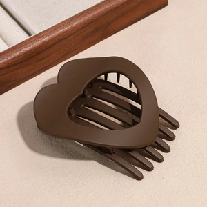 Detail of matte coffee heart hair claw clip with strong teeth on leather background