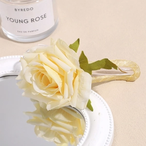 Detailed view of an elegant 3D cream fabric rose hair clip with gold glitter finish