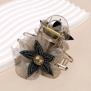Close-up of elegant hair claw with mesh petals and amber rhinestone center detail