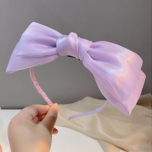 Detalle de una diadema con lazo morado en organza perlada de textura sedosa elegante