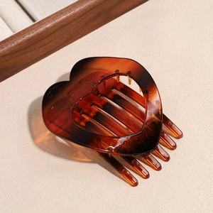 Detail view of heart-shaped amber acetate hair clip with tortoiseshell pattern finish
