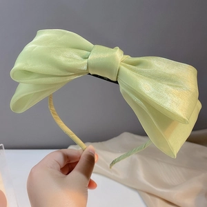 Detalle de diadema con lazo de organza verde claro con efecto perlado brillante