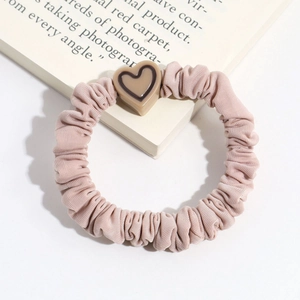 Detail of pink pleated scrunchie with a stylish resin heart charm on a white book