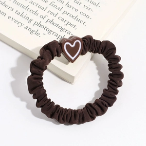 Close-up of brown pleated scrunchie with chocolate heart resin detail on a white book